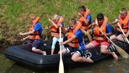 Mehrere Kinder paddeln in einem Schlauchboot. © NDR Foto: Jörg Thölke