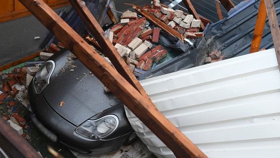 Teile eines eingestürzten Dachs liegen auf einem Porsche. © dpa Foto: Lars-Josef Klemmer