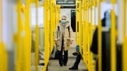 Eine Frau steigt mit einer OP-Maske in eine Bahn. © picture alliance/dpa Foto: Christoph Soeder