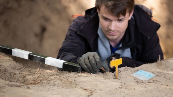 Ein Archäologe, hält bei einer archäologischen Grabung auf dem Gelände der Varusschlacht ein Fundstück in der Hand. © dpa-Bildfunk Foto: Friso Gentsch