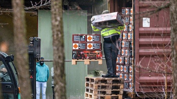 Polizisten entladen bei einer Razzia bei einer Bunkeranlage in Bad Bentheim einen Container mit Feuerwerkskörpern. © Friso Gentsch/dpa Foto: Friso Gentsch/dpa