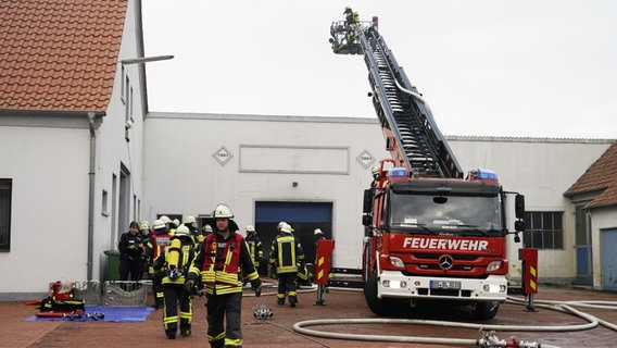 Einsatzkräfte der Feuerwehr stehen vor einer Lagerhalle in Bad Essen. Einsatzkräfte der Feuerwehr stehen vor einer Lagerhalle in Bad Essen. © Nord-West-Media TV