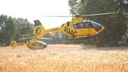 Ein Rettungshubschrauber des ADAC startet auf einem Feld neben einem zweiten Hubschrauber. © Nord-West-Media TV 