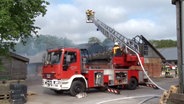 Feuerwehrleute löschen ein brennendes landwirtschaftliches Gebäude in Berge © Nord-West-Media TV 