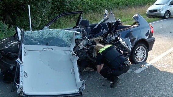 Eine Polizistin untersucht ein Autowrack nach einem Unfall auf der B68. © Nord-West-Media TV 