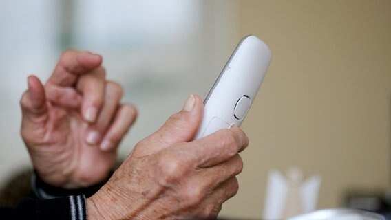 Ein Senior hält einen Telefonhörer in der Hand. © dpa-Bildfunk Foto: Roland Weihrauch