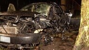 Ein stark zerstörtes Auto steht neben einem Baum. © Nord-West-Media TV 