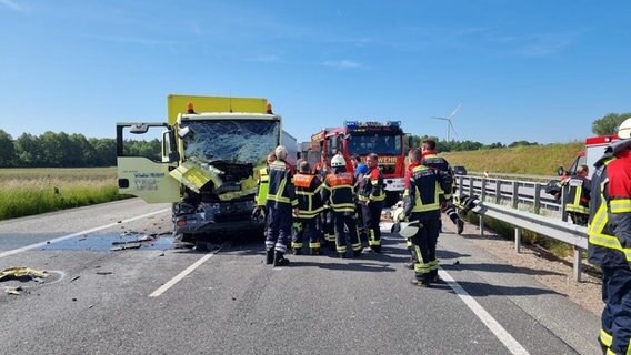 Feuerwehrleute stehen nach einem Unfall neben einem Lkw auf der A1. © Nord-West-Media TV 