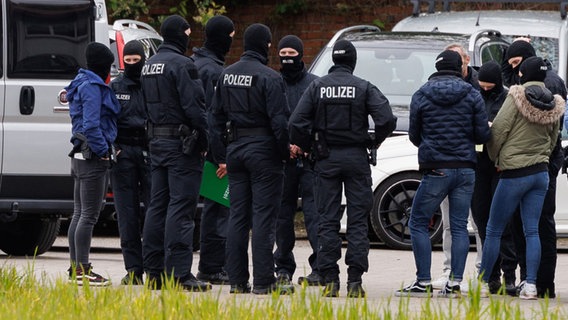 Bramsche: Polizisten tragen Masken, während sie auf einem Firmengelände stehen, auf dem mehrere Autos sichergestellt wurden. © dpa-Bildfunk Foto: Friso Gentsch