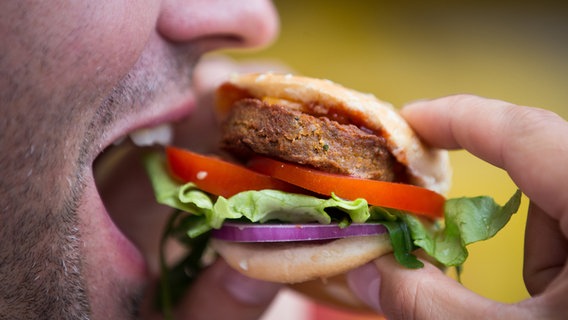 Eine Person beißt in einen Burger. © dpa Bildfunk Foto: Friso Gentsch