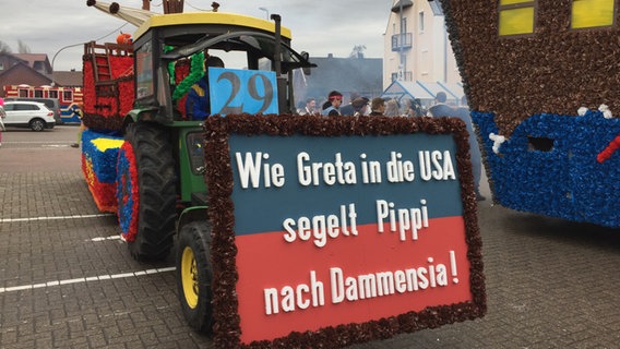 Beim Fastnachtsumzug beim Dammer Carneval ist ein geschmückter Trekker mit der Aufschrift "Wie Greta in die Usa segelt Pippi nach Dammensia." © NDR Foto: Thomas Schwierzi