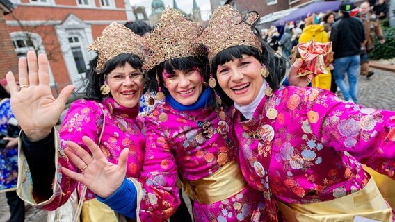 Drei bunt verkleidete Frauen lachen während des Fastnachtumzugs des Dammer Carnevals fröhlich in die Kamera. © dpa - Bildfunk Foto: Hauke-Christian Dittrich