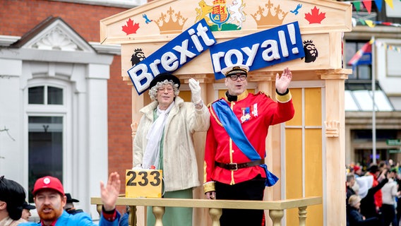 Zwei verkleidete Personen stehen vor einem Wagen mit der Aufschrift "Brexit royal!" beim Fastnachtumzug des Dammer Carnevals. © dpa - Bildfunk Foto: Hauke-Christian Dittrich
