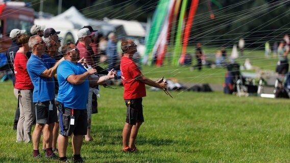 Eine Gruppe von Drachenlenkern steuert ihre Lenkdrachen auf dem Drachenfest in Melle 2023 © dpa Bildfunk Foto: Friso Gentsch