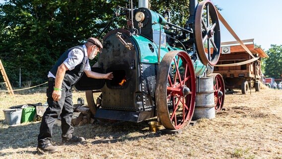 Beim Historischen Feldtag in Nordhorn befeuert Wolfgang Ressel ein aus dem Jahr 1912 mit Dampf angetriebenes Lokomobil der Firma Lanz. © dpa Foto: Guido Kirchner