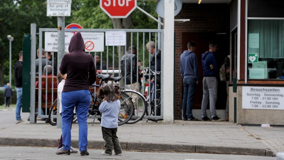 Flüchtlinge stehen am Haupteingang der Landesaufnahmebehörde Niedersachsen in Bramsche. © Picture Alliance Foto: Ingo Wagner