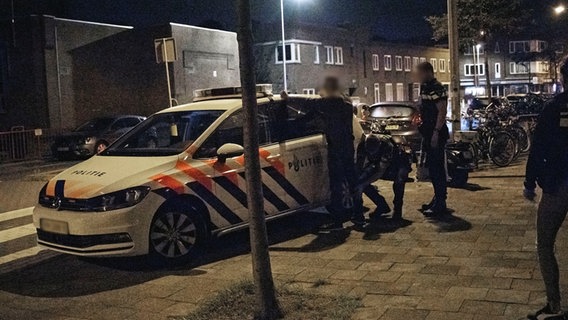 Niederländische Polizisten untersuchen einen Verdächtigen an einem Polizeifahrzeug. © Polizeidirektion Osnabrück 