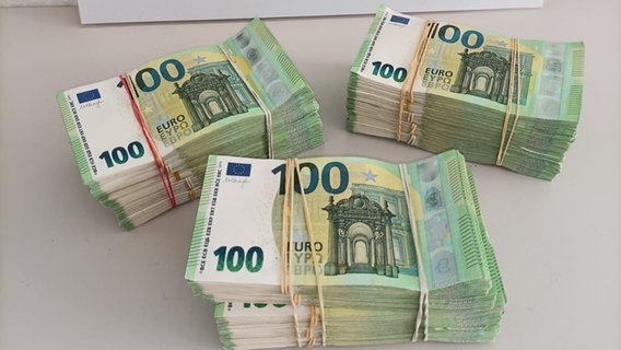 150.000 Euro in Hundert-Euro-Scheinen, die bei einer Kontrolle der Polizei auf der A30 bei Bad Bentheim wegen des Verdachts der Geldwäsche beschlagnahmt wurden, liegen auf einem Tisch im Hauptzollamt Osnabrück. © Polizei Osnabrück 