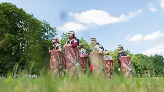 Römische Darsteller stehen bei den Römer- und Germanentagen auf einer Wiese. © dpa-Bildfunk Foto: Guido Kirchner/dpa