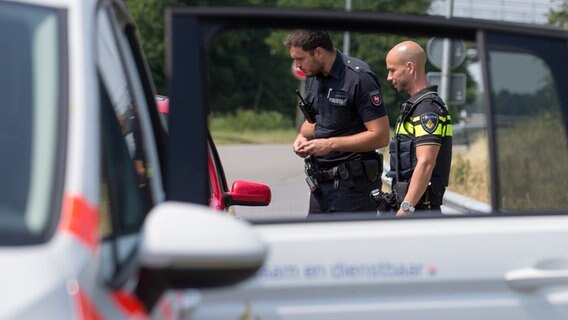 Polizisten aus Deutschland und der Niederlande kontrollieren ein Auto bei einer Großkontrolle. © dpa Foto: Friso Gentsch