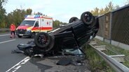 Ein Pkw liegt nach einem Unfall auf dem Kopf an einer Schallschutzwand auf der B68. © Nord-West-Mediat TV 
