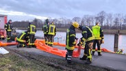 Feuerwehrleute bereiten eine Ölsperre am Dortmund-Ems-Kanal vor. © Nord-West-Media TV 