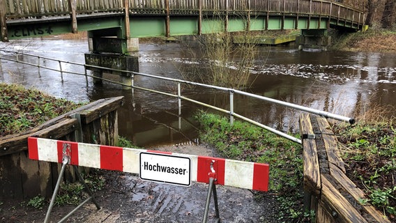 Eine Absperrung mit der Aufschrift "Hochwasser" steht vor der Hunte bei Wildeshausen. © NDR Foto: Thomas Schwierzi