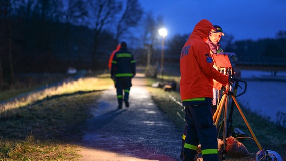 Ehrenamtliche Einsatzkräfte des Technischen Hilfswerks (THW) bauen im Hochwassergebiet an der Ems eine Mobile Lichtanlage auf, um einen Deich auszuleuchten. © Lars Penning/dpa Foto: Lars Penning
