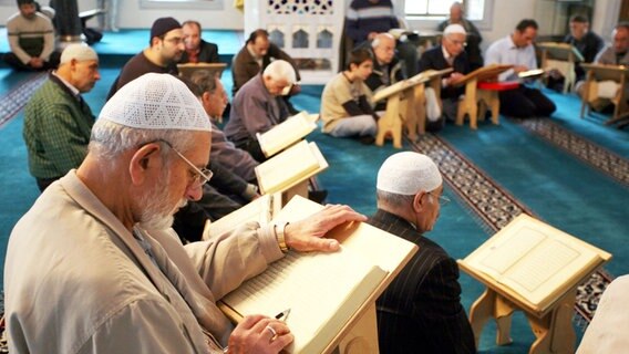 Muslime lesen am "Tag der offenen Moschee" in der Sehitlik-Moschee am Columbiadamm in Berlin in einem Koran. © dpa Foto: Rainer Jensen