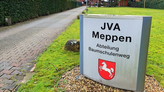 Ein Schild der JVA Meppen vor dem Gebäude des offenen Vollzugs ohne Gitter, Mauer oder Stacheldraht davor. © NDR Foto: Susanne Schäfer