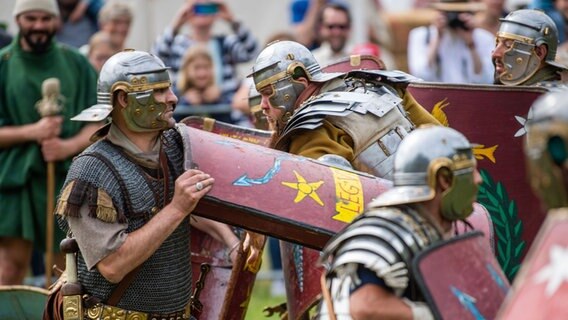 Darsteller in Kostümen der Römischen Legion "Ferrata" kämpfen in einer Arena. © dpa Foto: Lino Mirgeler