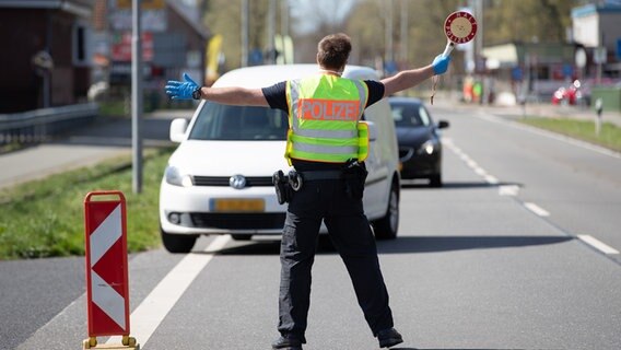 Ein Beamter der Bundespolizei winkt mit einer Kelle an der Grenze zu den Niederlanden einen Pkw raus. © dpa - Bildfunk Foto: Friso Gentsch