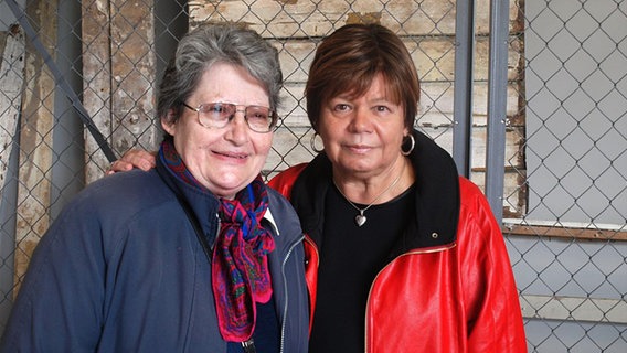 Zwei Frauen stehen Arm in Arm vor einem Stacheldrahtzaun. © NDR Foto: Hedwig Ahrens