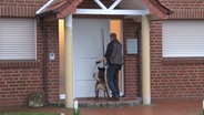 Ein Polizist mit einem Suchhund vor einem Wohnhaus in Lingen © Nord-West-Media TV 