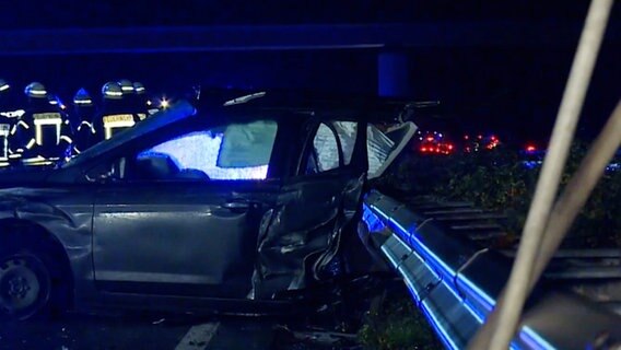 Rettungskräfte stehen nach einem schweren Unfall auf der A31 bei Lingen hinter einem stark beschädigten Pkw. © Nordwestmedia TV 