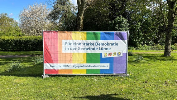 An einem Bauzaun hängt ein buntes Banner gegen rechts mit der Aufschrift "Für eine starke Demokratie in der Gemeinde Lünne". © Samtgemeinde Spelle Foto: Samtgemeinde Spelle