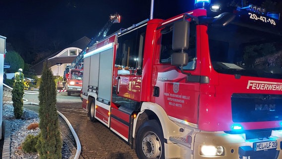 Einsatzfahrzeuge der Feuerwehr stehen vor einem Haus in Melle. © Nord-West-Media TV/dpa Foto: David Poggemann