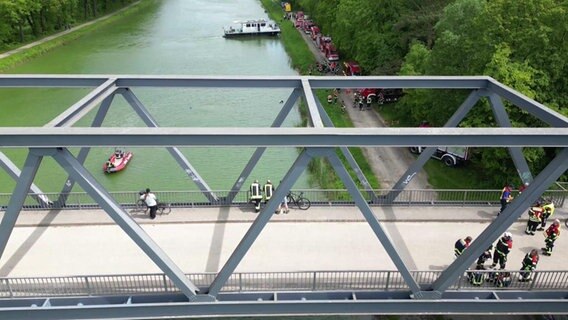 Einsatzkräfte auf einer Brücke und am Ufer des Mittellandkanals bei Bramsche. Hier ist ein Sportboot mit einem Binnenschiff kollidiert und gesunken. © TV7News 