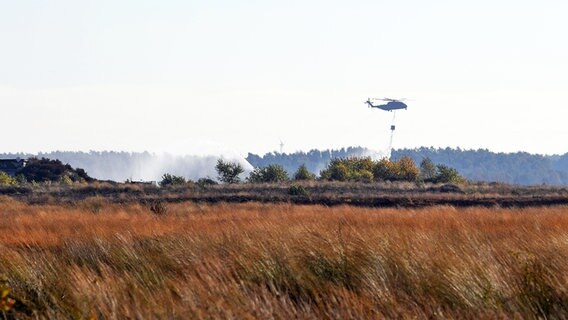 Ein Hubschrauber lässt Löschwasser über einer Moorlandschaft nieder. © dpa-Bildfunk Foto: Carmen Jaspersen