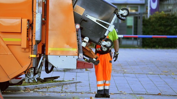 Ein Mitarbeiter der Müllentsorgung steht hinter einem Müllauto. © picture alliance / SvenSimon Foto: Frank Hoermann/SVEN SIMON