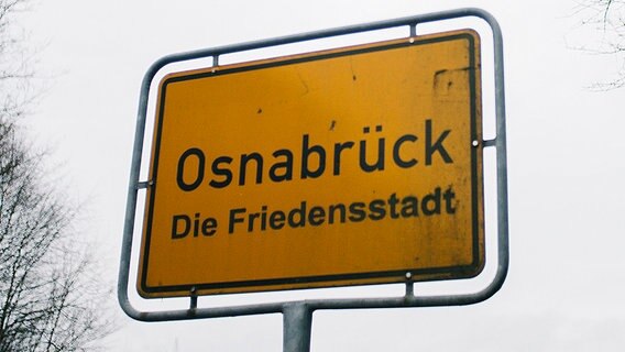Am Ortseingang von Osnabrück steht eine gelbe Ortstafel vor grauem Himmel. © NDR Foto: Julius Matuschik