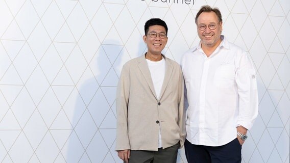 Top chef Thomas Bühner (r) and the new head chef Xavier Yeung stand in front of the lettering of the restaurant 