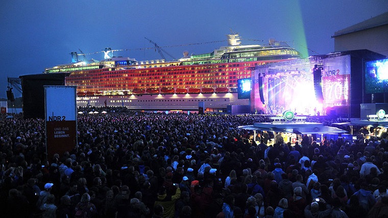 Vor dem farbig beleuchteten Kreuzfahrtschiff-Neubau "Celebrity Silhouette" an der Ausrüstungspier der Meyer-Werft, tritt die deutsche Rockgruppe "The Scorpions" auf der NDR 2 Festivalbühne auf. Vor dem farbig beleuchteten Kreuzfahrtschiff-Neubau "Celebrity Silhouette" an der Ausrüstungspier der Meyer-Werft, tritt die deutsche Rockgruppe "The Scorpions" auf der NDR 2 Festivalbühne auf. © dpa Fotograf: Ingo Wagner