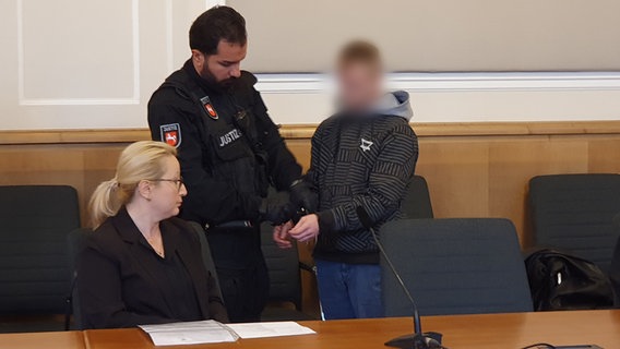 Der Angeklagte eines Mordprozesses im Landgericht Osnabrück neben seiner Dolmetscherin und einem Beamten des Justizvollzugs © NDR Foto: Susanne Schäfer