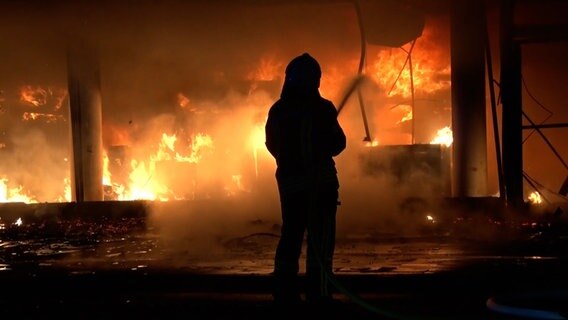 Einsatzkräfte der Feuerwehr löschen ein brennendes Ladengeschäft. © Nord-West-Media TV 