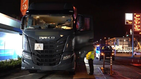 Ein Lkw steht an einer Straße und wird von Polizisten kontrolliert. © TV7News 