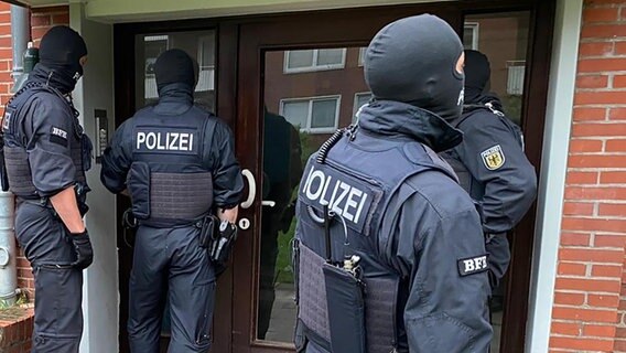 Vermummte Polizisten stehen vor einer Haustür. © Bundespolizei 