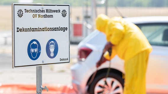 Mitarbeiter vom Technischen Hilfswerk reinigen und desinfizieren ein Fahrzeug in einer Dekontaminationsanlage. © dpa-Bildfunk Foto: Friso Gentsch