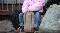 Ein Kind sitzt auf einem vollbepackten Koffer in der Erstaufnahme für Flüchtlinge in Osnabrück.  Foto: Kora Blanken