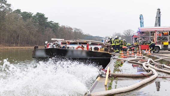 Die Feuerwehr pumpt ein mit Wasser vollgelaufenes Binnenschiff, dass an einer Keilmauer auf dem Dortmund-Ems Kanal in  Spelle liegt mit insgesamt vier Pumpen leer. © dpa-Bildfunk Foto: Guido Kirchner